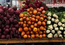 A vibrant display of beets, golden beets, and celery at a farmer's market stall.