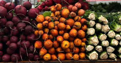 A vibrant display of beets, golden beets, and celery at a farmer's market stall.