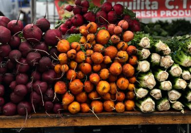 A vibrant display of beets, golden beets, and celery at a farmer's market stall.